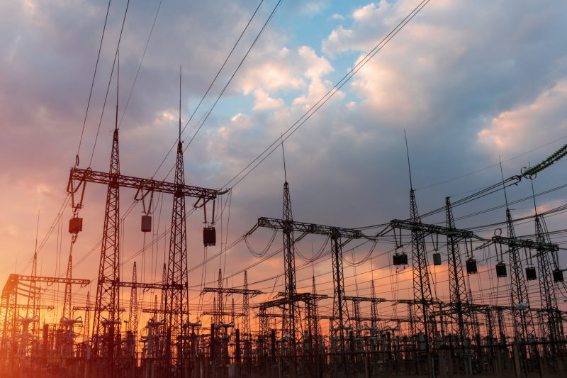 distribution electric substation with power lines and transformers, at sunset