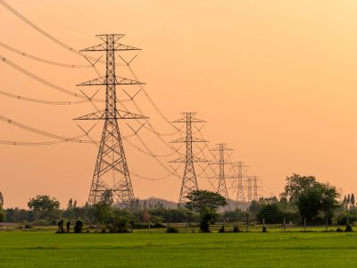 Arrangement of High voltage pole, Transmission tower on rice field in countryside at sunset